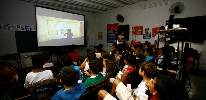 Cinema na escola: fotografia de uma sala de aula com estudantes assistindo um filme.