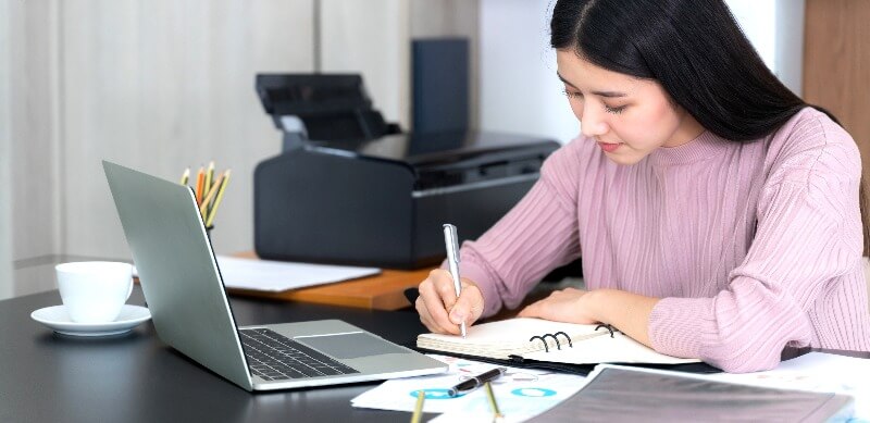 Como fazer um planejamento escolar: fotografia de uma mulher escrevendo em uma agenda.