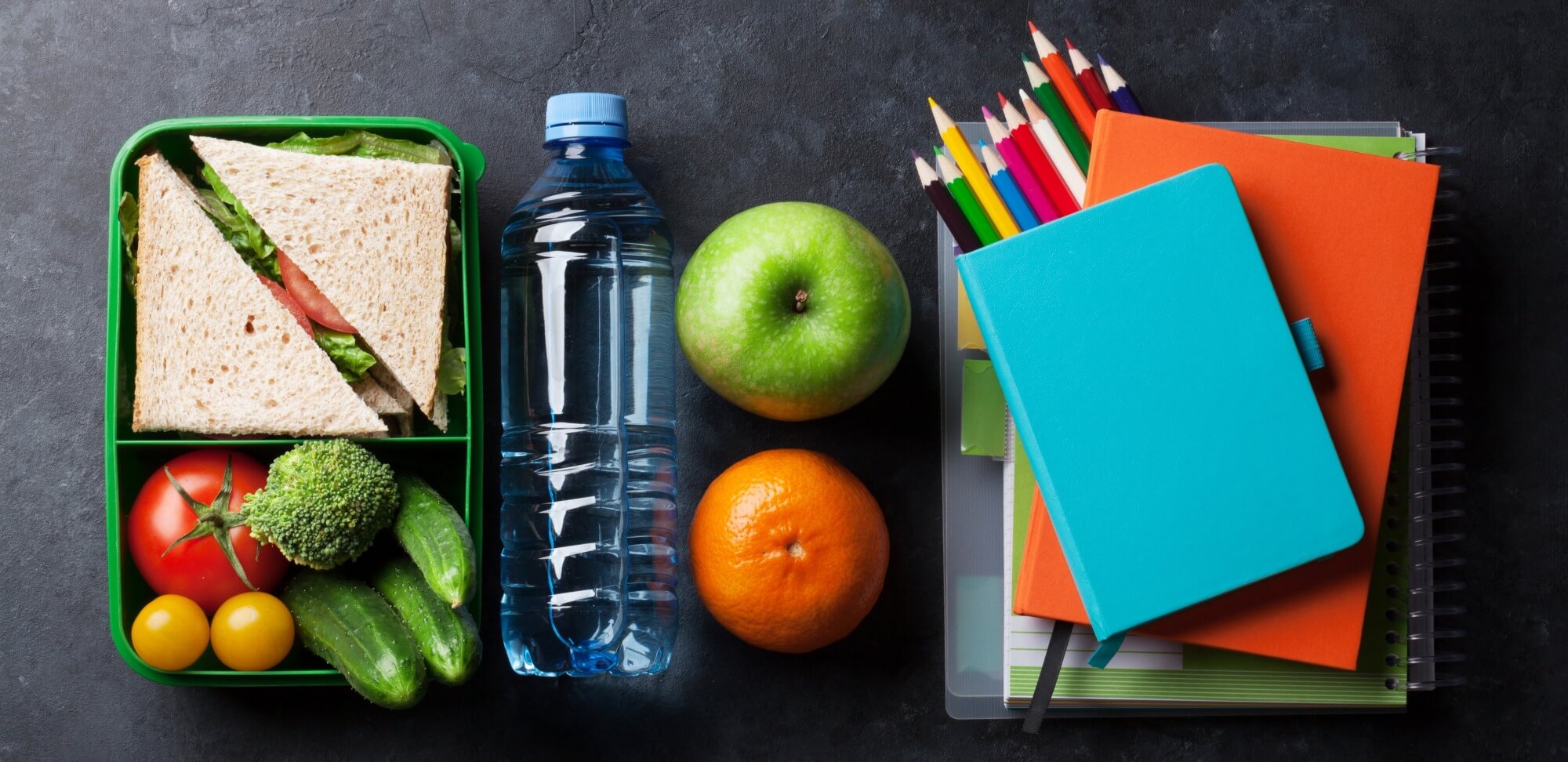 alimentação e desempenho escolar: imagem de frutas e aguá ao lado de livros, cadernos e lápis