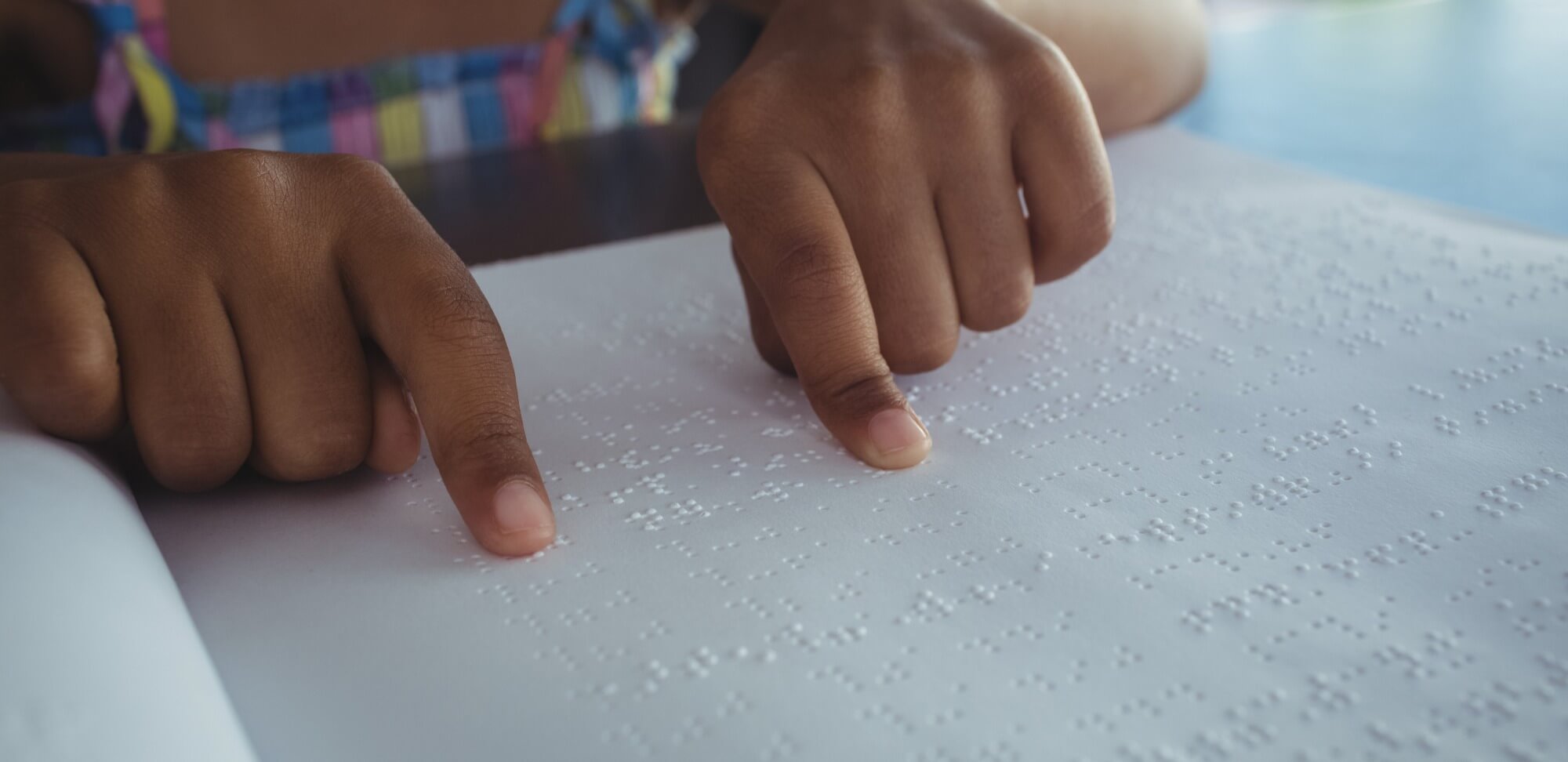 fundamentos e princípios da educação inclusiva: imagem de um aluno lendo em braille