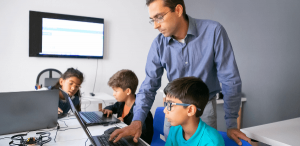 Como captar alunos na educação básica: imagem de professor ensinando seus alunos em um laboratório de informática.