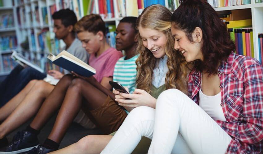 Como o Microlearning pode ajudar o desenvolvimento no ensino básico: imagem de estudantes lendo livros e mexendo no celular