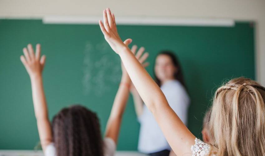 Storytelling na educação: crianças na sala de aula levantando a mão