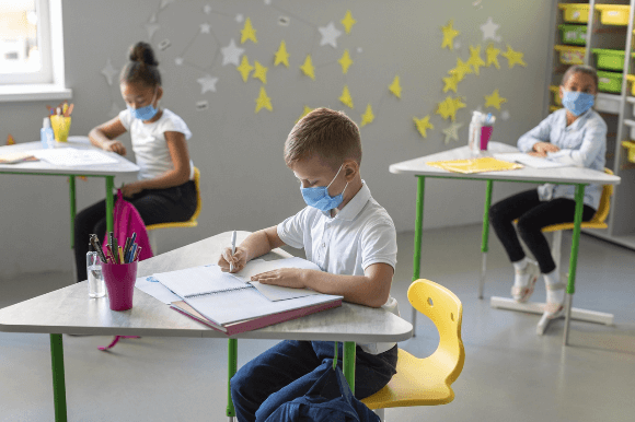 Educação pós-pandemia: crianças de máscara realizando atividades em sala