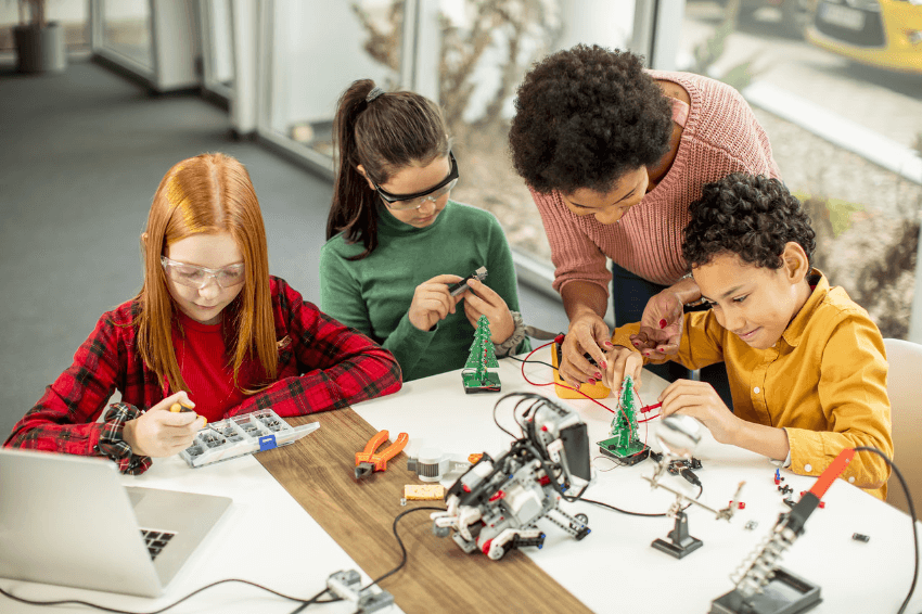 Cultura digital: grupo de crianças programando brinquedos e robôs com a ajuda da professora