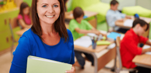 Microlearning: imagem de de uma professora com um caderno em mãos mostrando ao fundo seus alunos em sala de aula